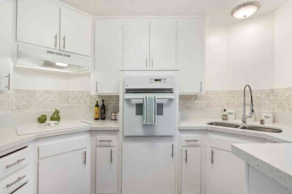 renovated kitchen with white cabinetry and tile backsplash