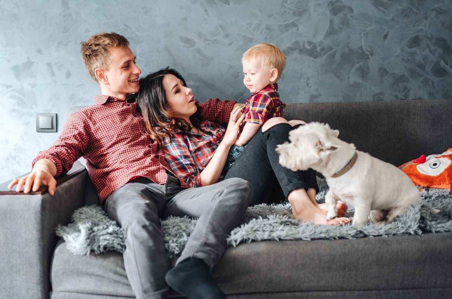 Family relaxing on a couch with their small white dog